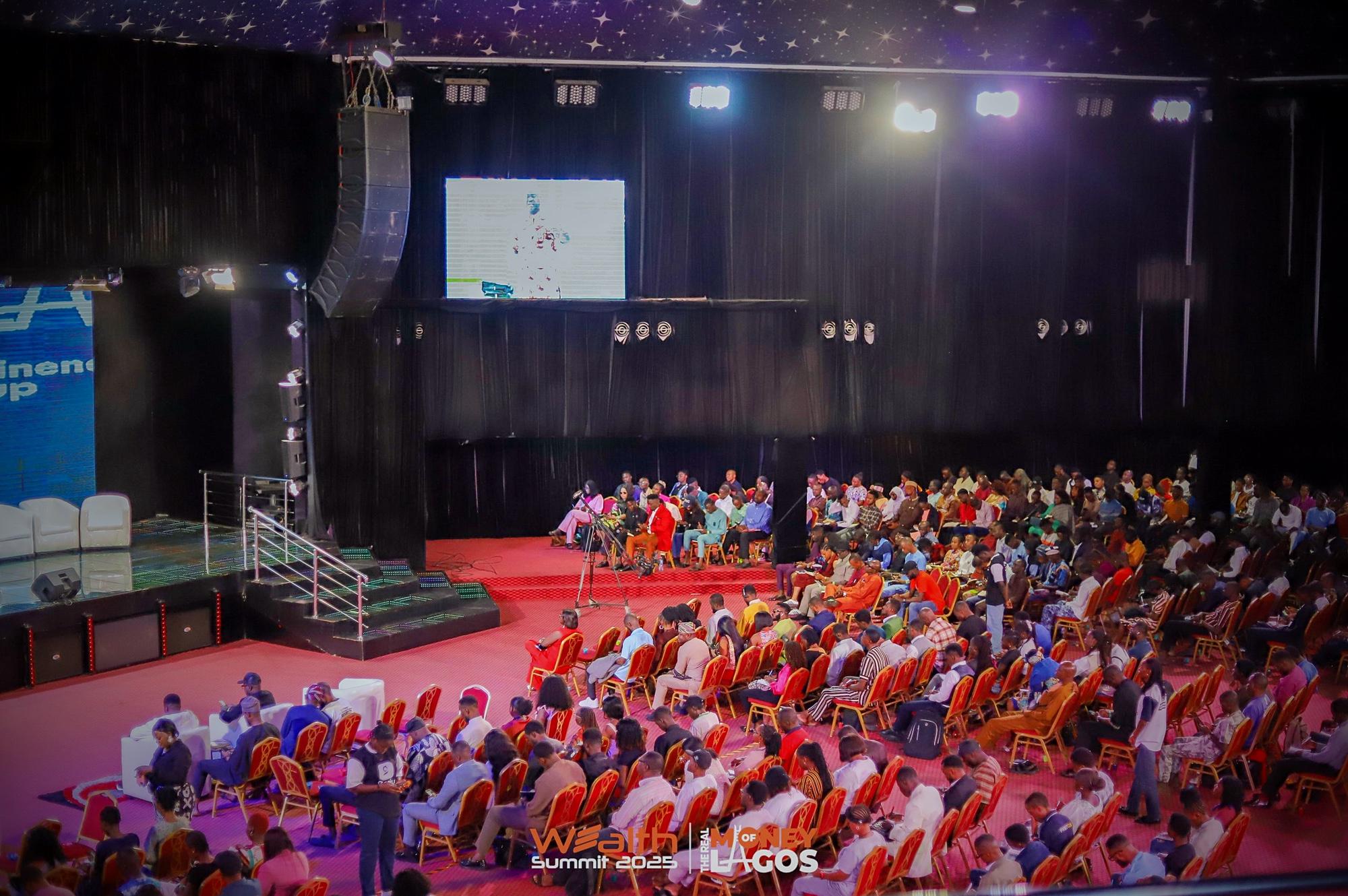 A packed hall of attendees in rows of orange chairs at the Wealth Summit in Lagos