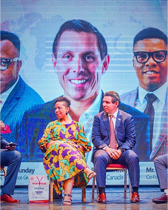 Dr. Sunday Olorunsheyi on a panel stage in front of a Canadian-flag screen