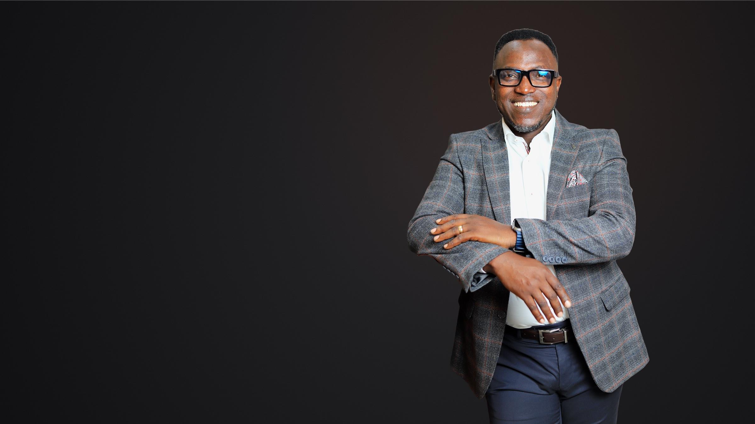 Dr. Sunday Olorunsheyi in a plaid blazer, smiling warmly