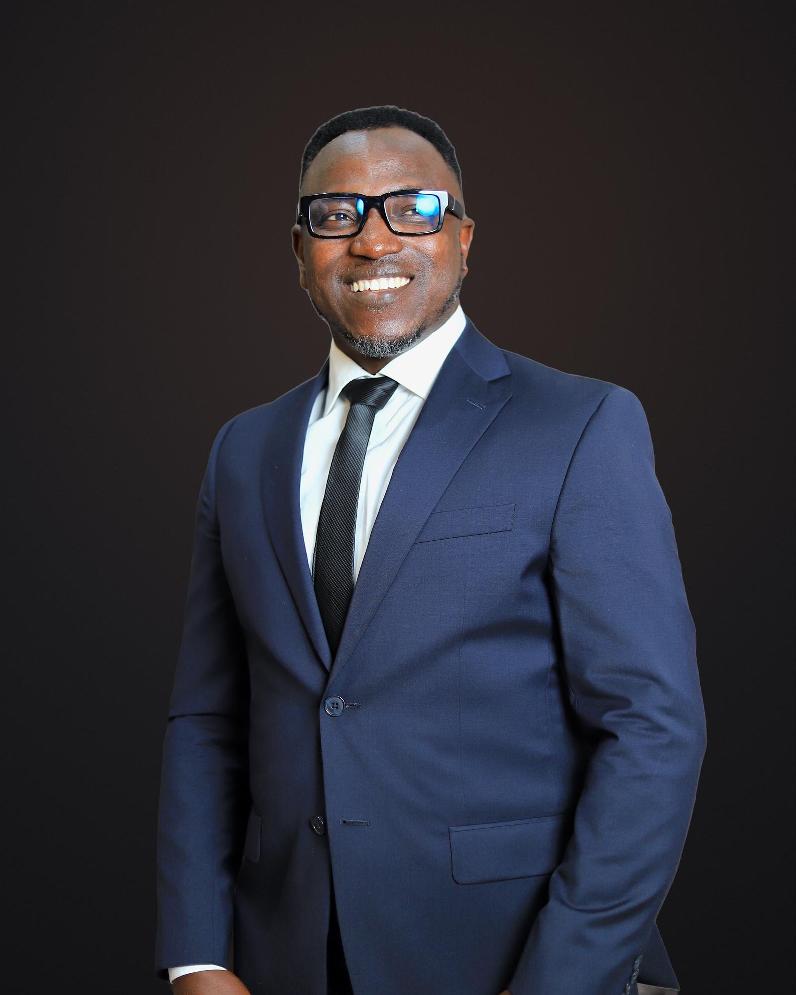 Portrait of Dr. Sunday Olorunsheyi in a navy suit and black tie